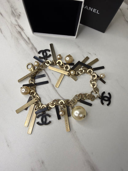 Chanel Logo Charm Bracelet featuring gold and black metal charms and faux pearls