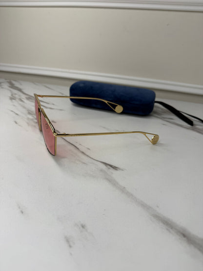 Gucci GG0437SA sunglasses featuring a gold metal frame and pink lenses