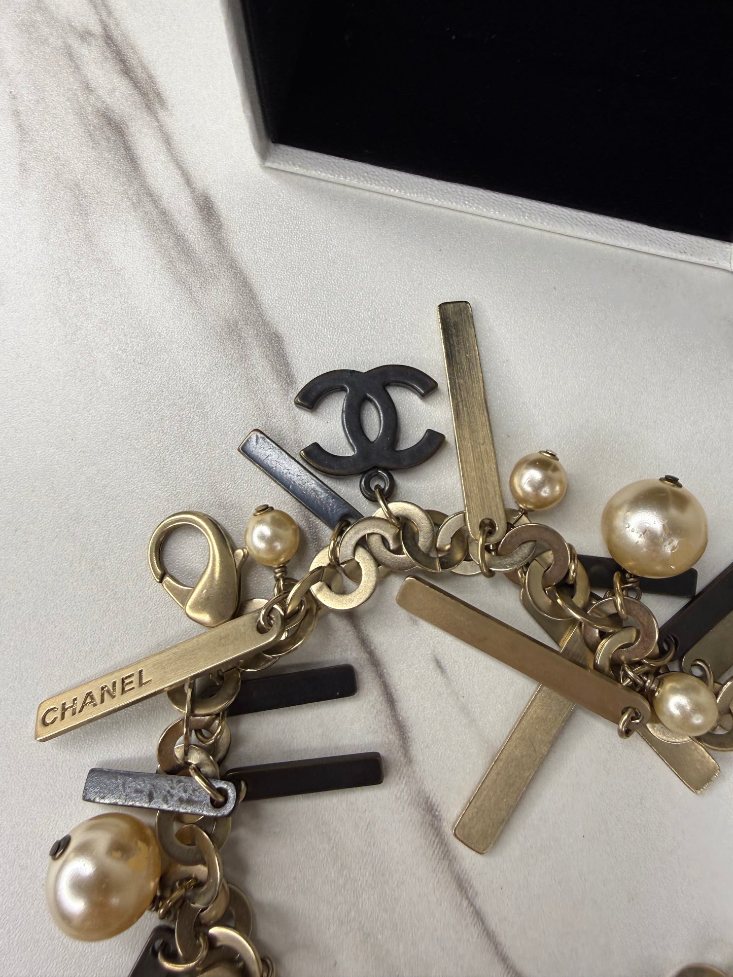 Chanel Logo Charm Bracelet featuring gold and black metal charms and faux pearls