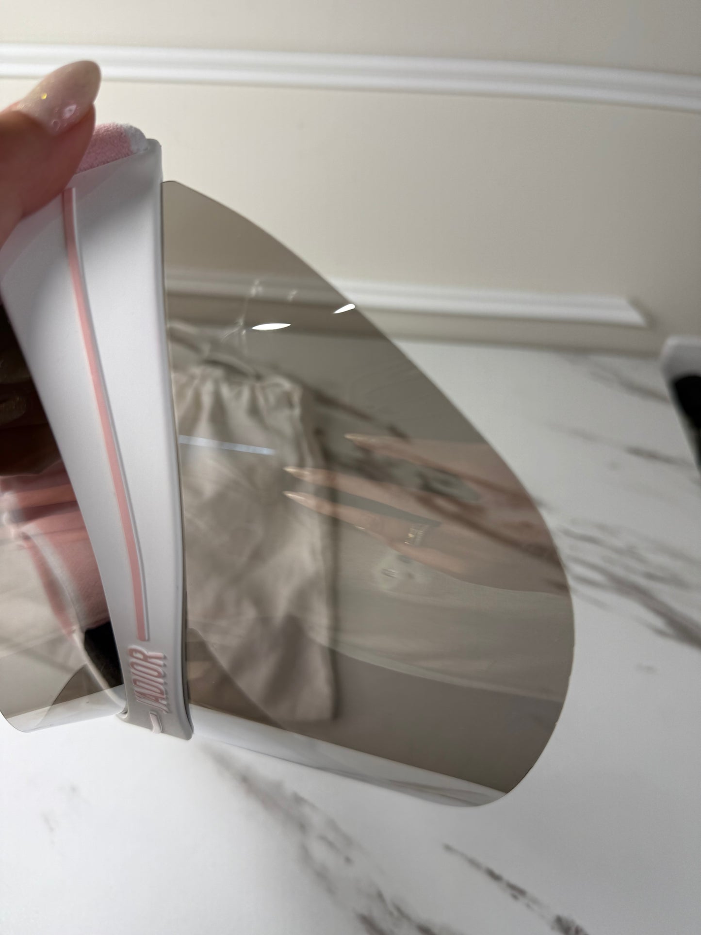 Dior Club 1 sun visor in pink and white with a grey lens