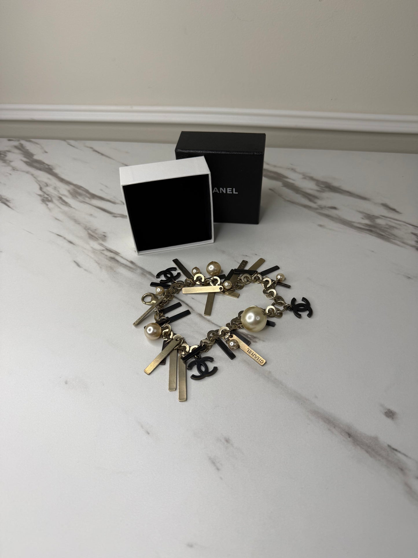 Chanel Logo Charm Bracelet featuring gold and black metal charms and faux pearls