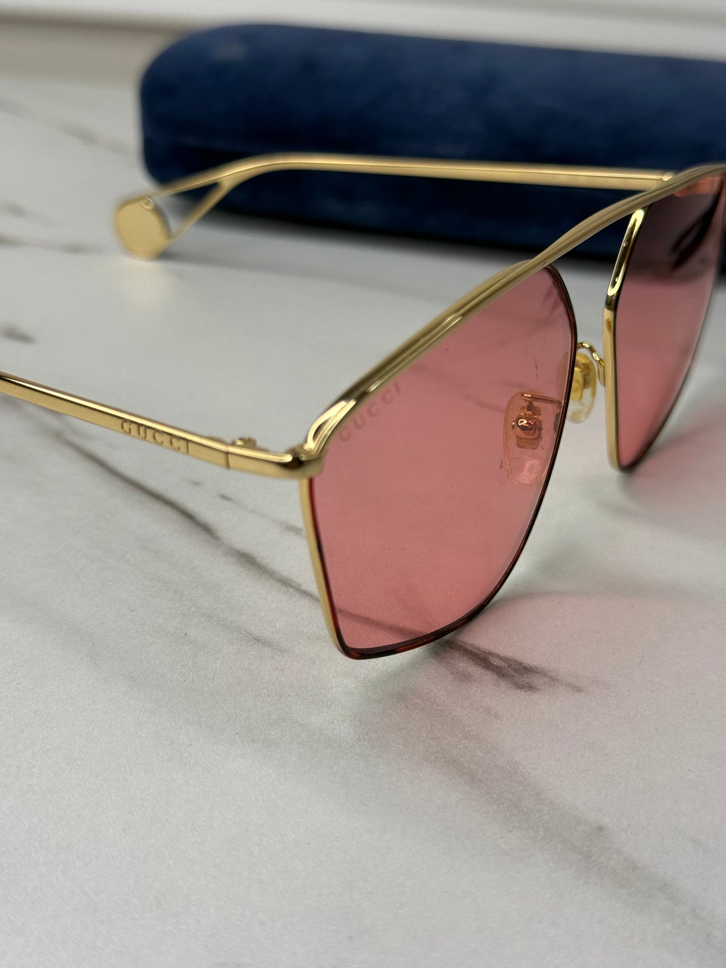 Gucci GG0437SA sunglasses featuring a gold metal frame and pink lenses