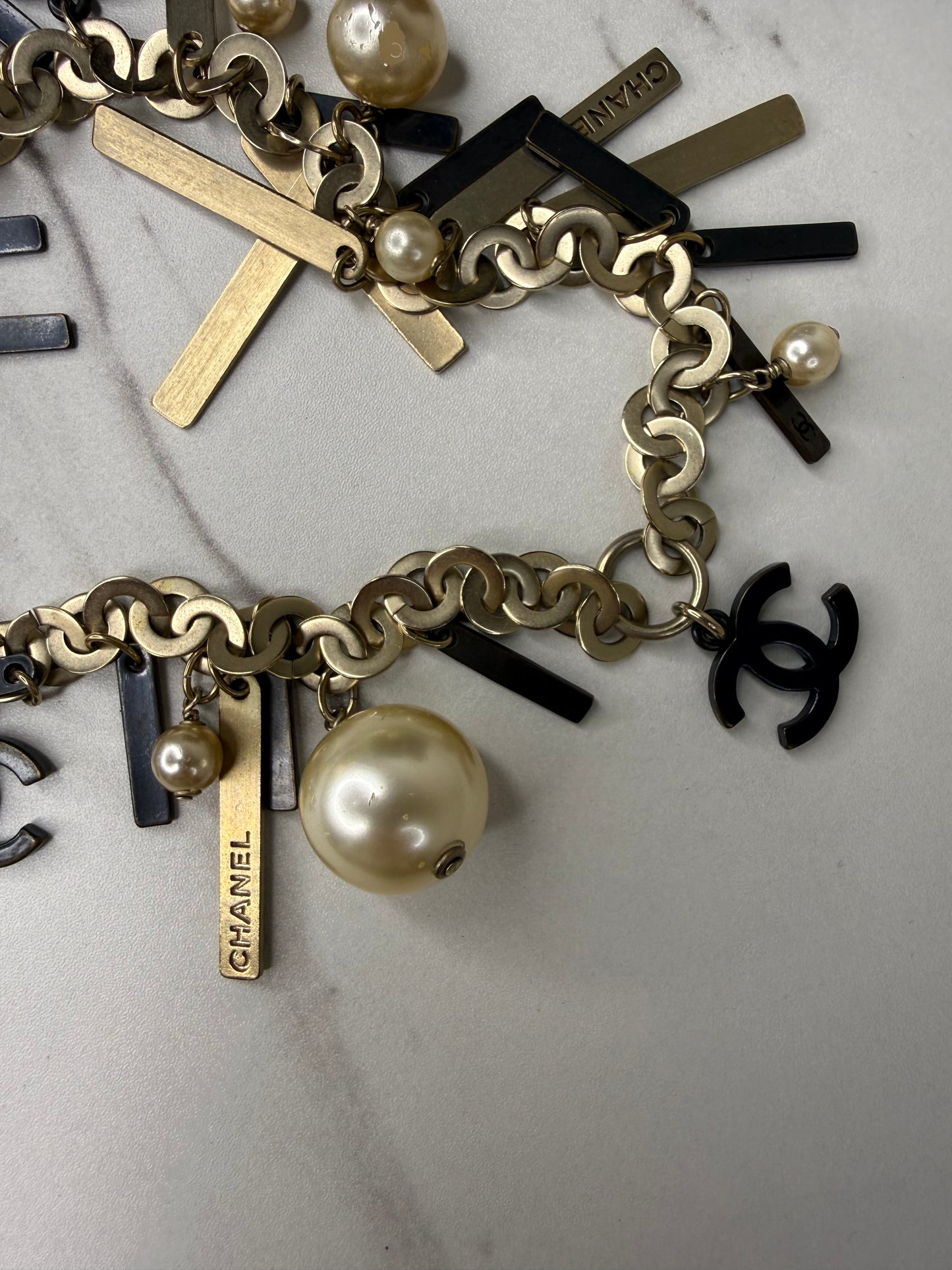 Chanel Logo Charm Bracelet featuring gold and black metal charms and faux pearls