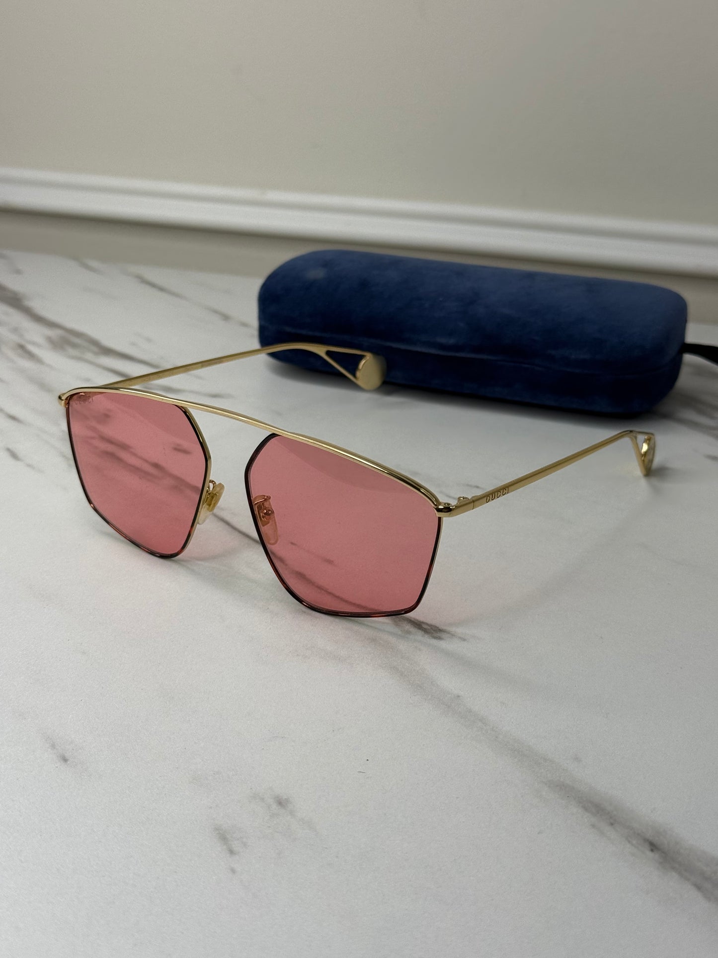 Gucci GG0437SA sunglasses featuring a gold metal frame and pink lenses