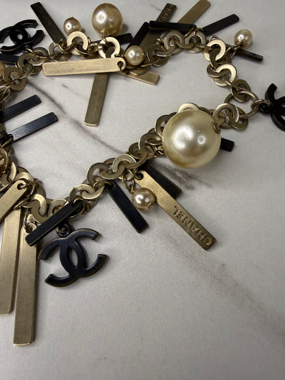 Chanel Logo Charm Bracelet featuring gold and black metal charms and faux pearls