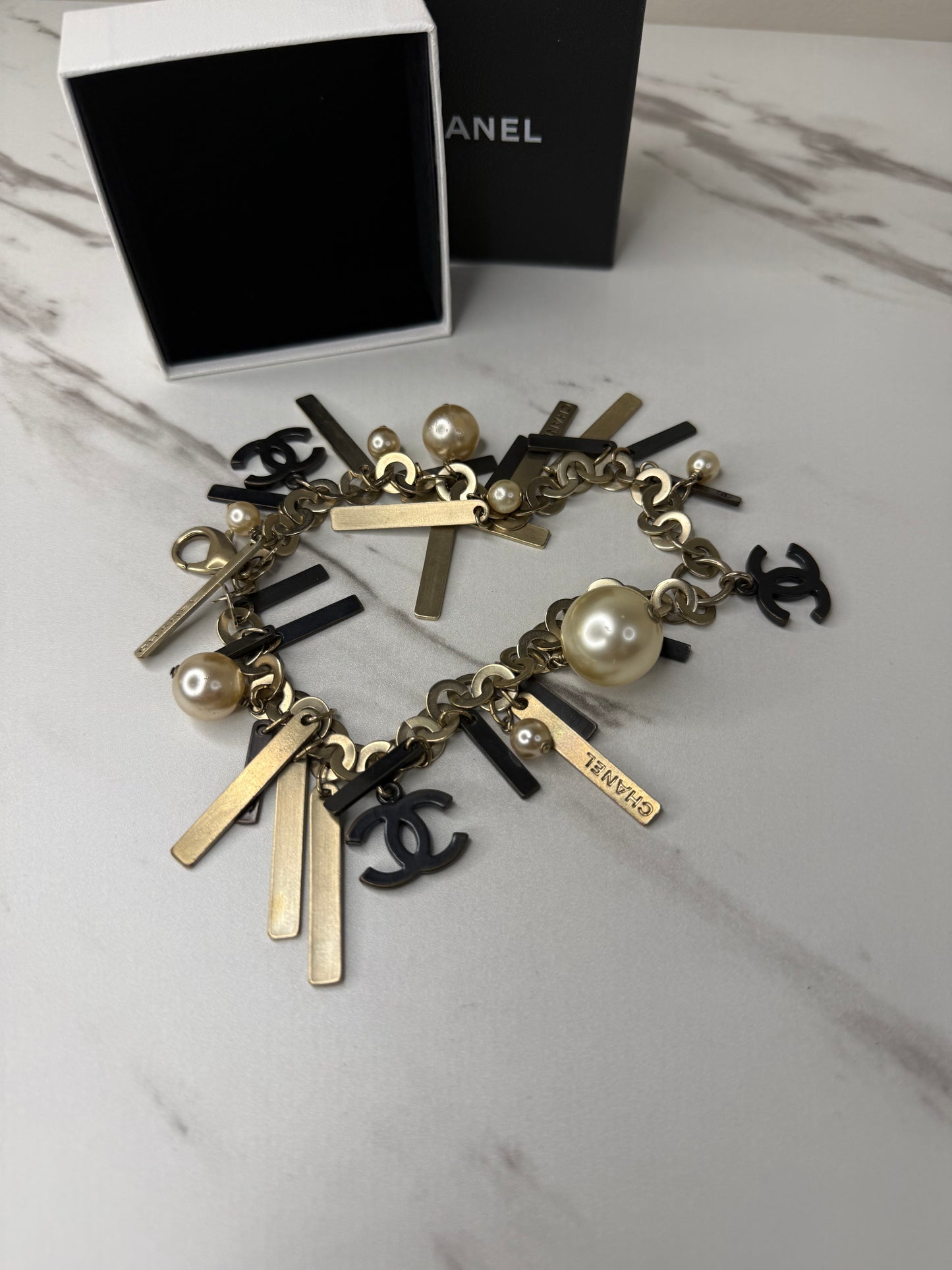 Chanel Logo Charm Bracelet featuring gold and black metal charms and faux pearls