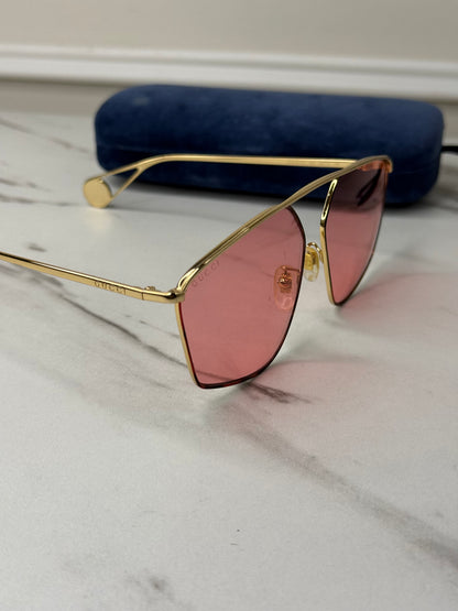 Gucci GG0437SA sunglasses featuring a gold metal frame and pink lenses