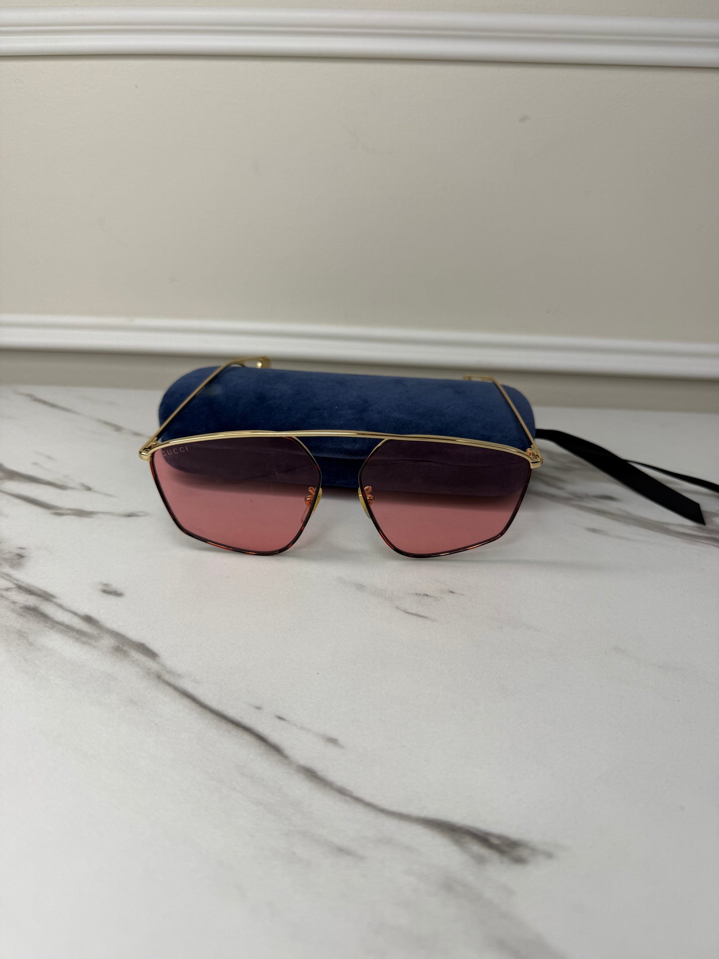 Gucci GG0437SA sunglasses featuring a gold metal frame and pink lenses